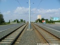 Tramvajová trať za protisměrnými zastávkami Depo Hostivař v otevřeném svršku ve středu Černokostelecké ulice stoupá na most nad železničními tratěmi.