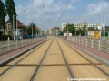 Prostor kolejiště protisměrných zastávek Černokostelecká kryje žlutá betonová dlažba.