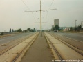 Původní podoba tramvajové tratě v úseku smyčka Ústřední dílny DP - smyčka Černokostelecká s rozpadajícím se asfaltovým zákrytem a zastávkami bez nástupních ostrůvků. | 20.8.1995