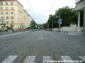 Tramvajová trať klesá Jičínskou ulicí k Olšanskému náměstí, vpravo se objevuje hřbitovní zeď Olšanských hřbitovů
