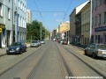 Přímý úsek tramvajové tratě ve staré zástavbě Nuselské ulice, tramvaje se zde doslova prodírají mezi parkujícími automobily.