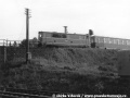 Osobní vlak vedený motorovou lokomotivou T 47.008 na náspu před železničním mostem přes tratě velké železnice do Černous a Jindřichovic pod Smrkem | 28.5.1975
