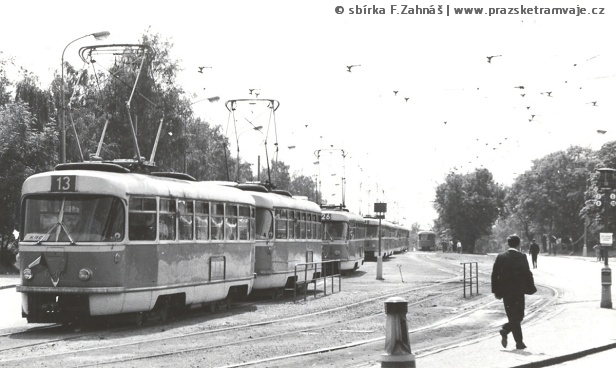 Zastávka vozovna Střešovice. Kvůli spartakiádě byla ke stadionu na Královku odkloněna také linka 13, na kterou byly již od 1. dubna 1965 nasazeny vlaky 2xT3. Byť je číslo předního vozu neúplné, dle 620x lze dohledat, že souprava byla vypravena na linku 13 vozovnou Pankrác. Z hlediska vozového parku se na této lince kvůli spartakiádě neměnilo nic. Za vlakem linky 13 vidíme sólo T3 na lince 26 a za ním další dvojici T3 na lince 13. Linka 26 byla jednou z těch linek, kde se v rámci spartakiádního provozu, resp. odklonu na Královku nasadily místo starých vlaků nové vozy T3. Na úrovni čela vozu vlaky linky 26 pak vidíme táhlo tzv. zajišťovací výhybky, která byla trvale postavena na cca 5 metrů dlouhou kusou kolej, která měla vykolejit tramvajový vlak, pokud by samovolně ujel z vozovny Střešovice. Při plánovaném průjezdu vlaku musel přítomný pracovník s pomocí táhla držet výhybku přestavenou na traťovou kolej. | červenec 1965